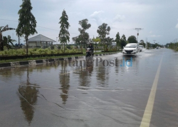 TERGENANG: Suasana  jalan poros Sangatta terendam banjir, Senin (19/2) kemarin.(Foto Dhedy/Sangatta Post)