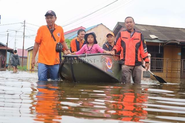 DERITA IBU KOTA: Petugas BPBD Samarinda mengevakuasi warga yang rumahnya terendam banjir di Jalan Terong, Samarinda Utara kemarin. Tampak rumah yang sudah ditinggal penghuninya. (RESTU/KP)