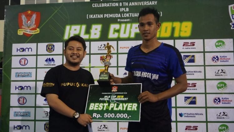 Staf Hubungan Eksternal Pupuk Kaltim, Catur Ramadhan MS (kiri) saat memberikan piala dan hadiah kepada pemain terbaik M Arifin. (Humas Pupuk Kaltim)