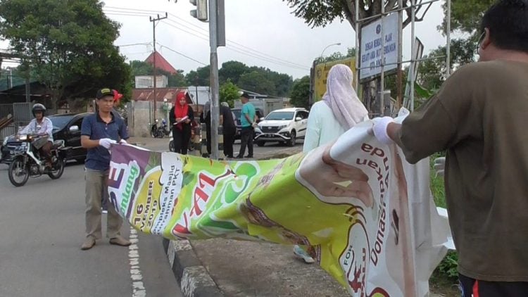 Tim Bapenda Bontang tengah menurunkan spanduk yang telah habis masa waktunya di beberapa titik pemasangan spanduk di Kota Taman. (Zaenul/Bontangpost.id)