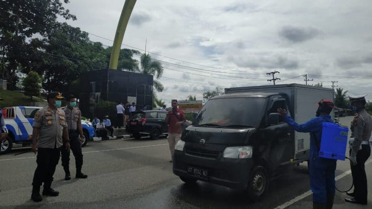 Polres Bontang bersama Pemkot Bontang melakukan pencegahan penyebaran covid-19 dengan cara penyemprotan disinfektan ke kendaraan yang masuk ke Kota Taman, Selasa (24/3/2020). (Zaenul/Bontangpost.id)