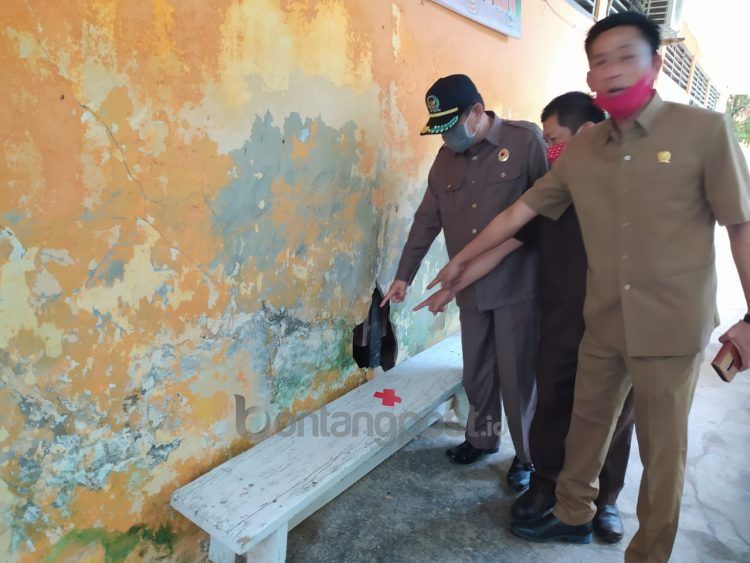 Anggota Komisi I DPRD Bontang menunjukkan kerusakan dinding bangunan sekolah saat meninjau kesiapan PJJ. (Adiel Kundhara/KP)