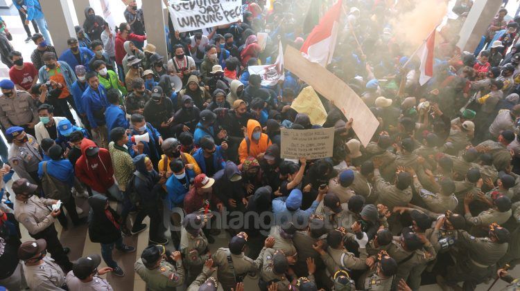 Massa aksi saling dorong dengan pihak keamanan. Massa meminta agar DPRD Bontang turut menolak pengesahan Omnibus Law, beberapa waktu lalu. (Fitri/bontangpost.id)