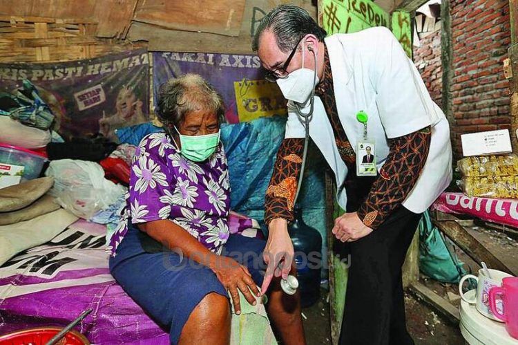 Michael Leksodimulyo berkomunikasi dengan perempuan yang akan ditanganinya. Dia konsisten memberikan layanan kesehatan gratis secara keliling. (ROBERTU RESKY/JAWA POS)