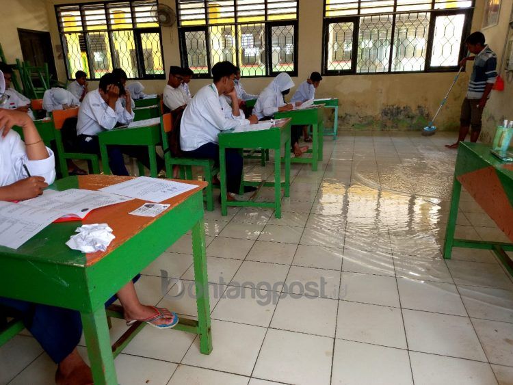 Pelajar MTS Al-Ikhlas mengikuti ujian nasional di tengah banjir rob yang merendam sekolah
