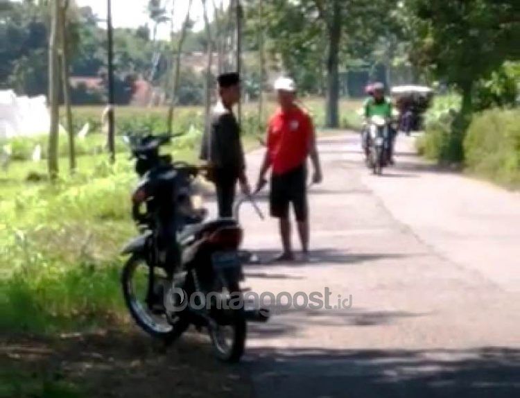 Tangkapan layar video dua orang yang sama-sama memegang senjata tajam. Peristiwa ini terjadi di jalan raya Desa Wringintelu, Kecamatan Puger, Jember. (Tangkapan layar)