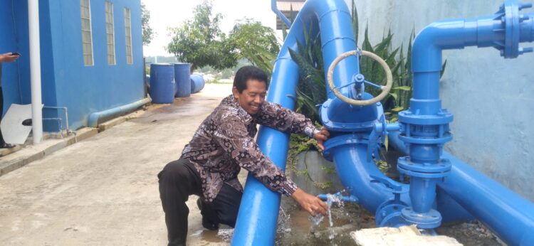 Direktur Perumda Tirta Taman Bontang Suramin menunjukkan hasil air limbah yang sudah diolah menjadi air bersih (Jelita/bontangpost.id)