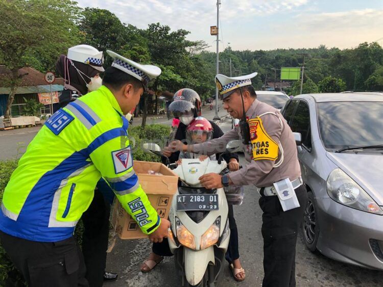 Kasat Lantas Polres Bontang (kanan) saat memberikan bunga kepada pengendara tertib berlalu lintas