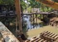 Jembatan kayu di Gang Atletik 3, Api-Api, dibongkar sementara selama pengerjaan normalisasi sungai untuk meminimalisasi dampak banjir (Nasrullah/bontangpost.id)