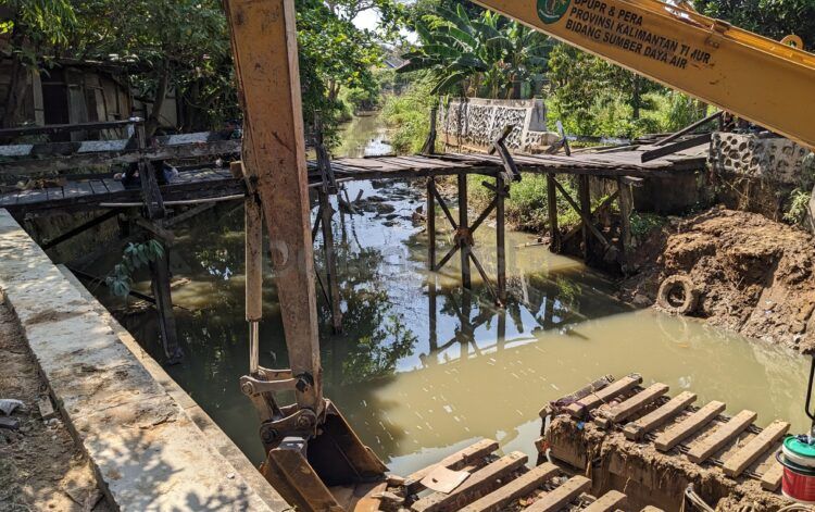 Jembatan kayu di Gang Atletik 3, Api-Api, dibongkar sementara selama pengerjaan normalisasi sungai untuk meminimalisasi dampak banjir (Nasrullah/bontangpost.id)