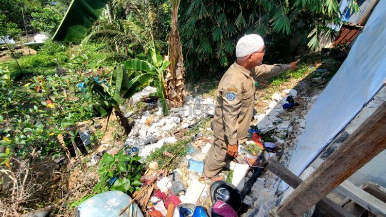 Jamal korban dinding ambruk di Berebas Tengah menunjukkan bagian tanah yang mulai tergerus dan dinding yang bolong akibat roboh (Lutfi/bontangpost)