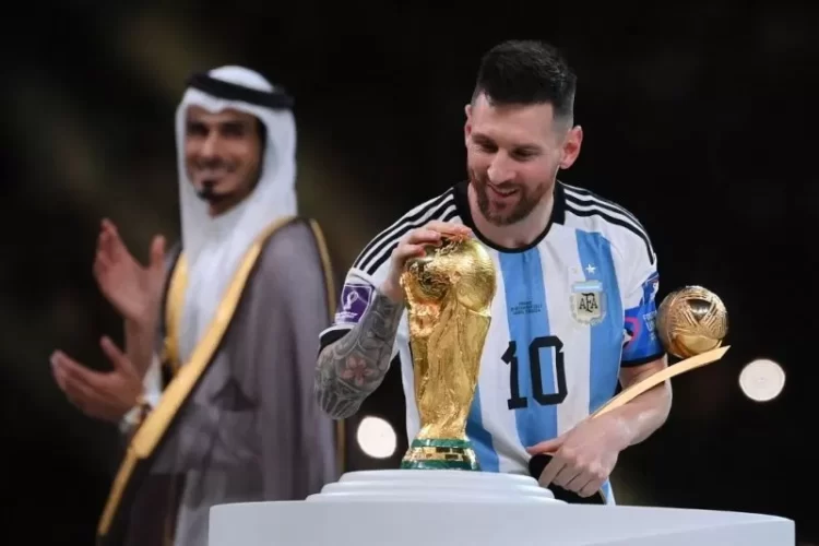Mega bintang Argentina Lionel Messi menyentuh trofi Piala Dunia setelah menerima anugerah Pemain Terbaik di Piala Dunia 2022 Qatar pada 18 Desember 2022. (Photo by FRANCK FIFE / AFP) (AFP/FRANCK FIFE)