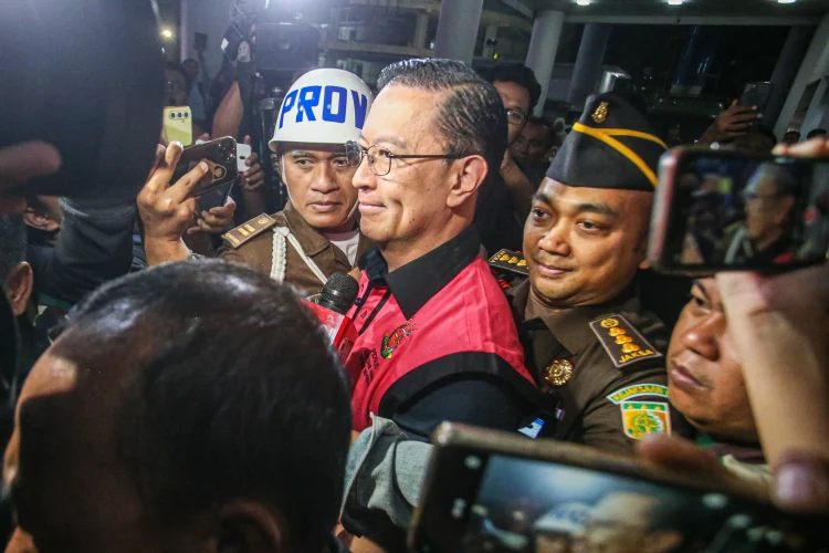 Menteri Perdagangan tahun 2015-2016 Thomas Lembong dibawa menuju mobil tahanan di Kejaksaan Agung, Jakarta, Selasa (29/10/2024). (Miftahul Hayat/ Jawa Pos)