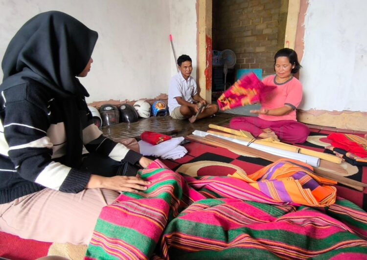 Sappe (tengah baju warna merah muda) di antara beragam karya indah kain tenun Toraja yang dibuatnya (Nasrullah/bontangpost.id)