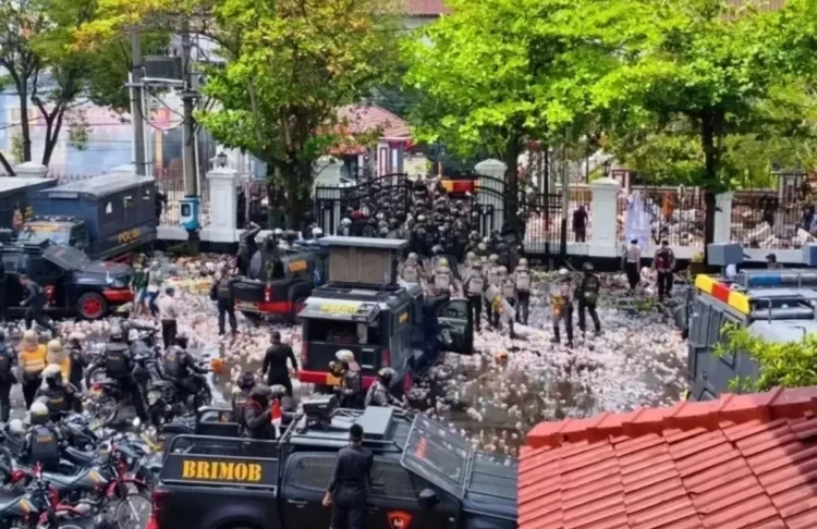 Aparat kepolisian berjaga di depan gerbang Pendopo Kabupaten Pati, Jawa Tengah, di tengah lautan botol plastik bekas lemparan massa saat aksi unjuk rasa. (Foto: Radar Kudus)