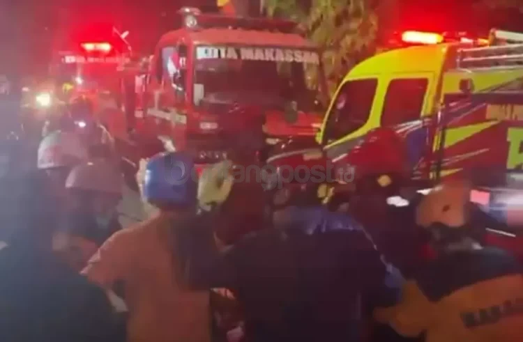 Petugas pemadam kebakaran bersama tim gabungan mengevakuasi korban di lokasi kebakaran Gedung DPRD Makassar, Jumat malam (29/8/2025). (Foto: Fajar)