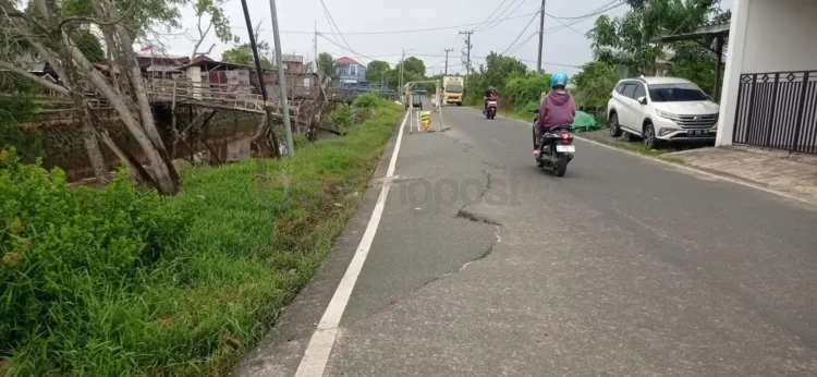 Jalan Koi menuju SMP 7 Bontang rusak dan miring di tepi sungai. Warga khawatir dan desak Pemkot segera lakukan perbaikan.