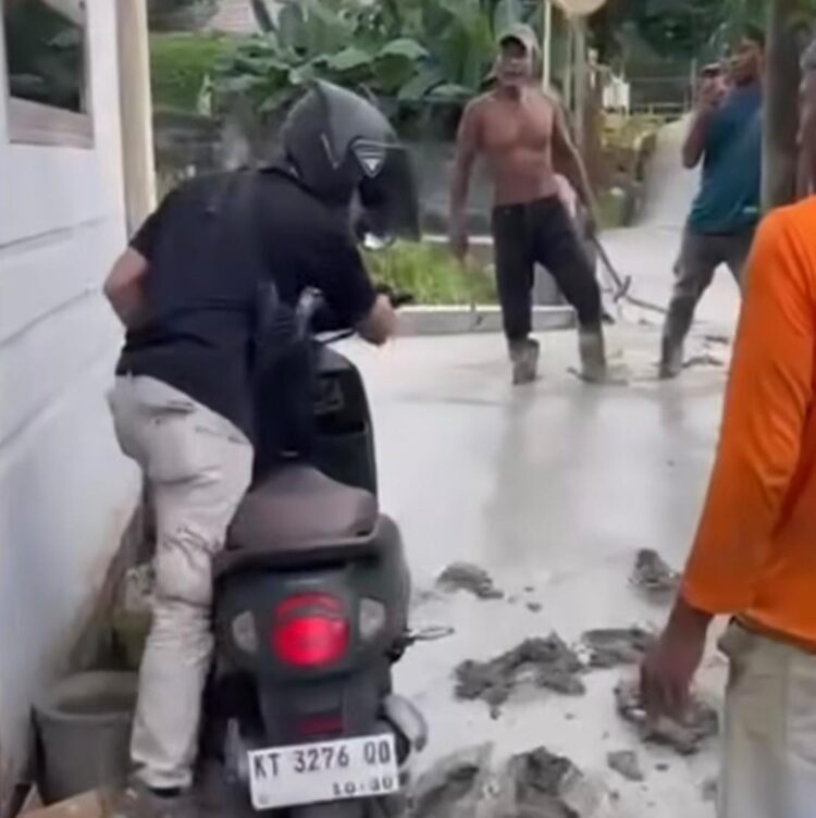 Tangkapan layar pengendara motor Scoopy hijau army yang nekat menerobos jalan sempit di RT 12 Kelurahan Guntung, Bontang, yang masih dalam proses semenisasi.