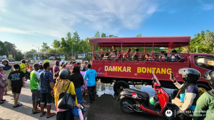 nak-anak sekolah dibantu personel Disdamkartan menyeberangi genangan banjir rob di Jalan Piere Tendean, Bontang Kuala, agar tetap dapat berangkat ke sekolah.