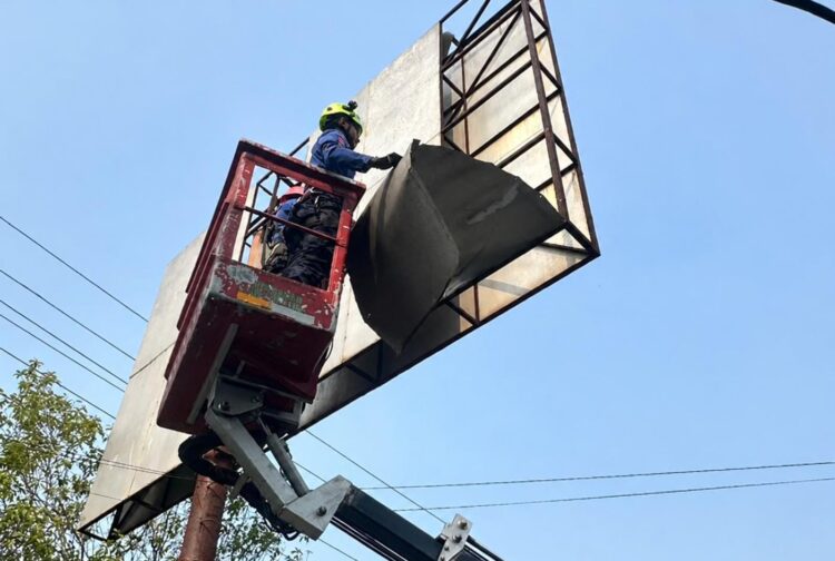 Petugas Disdamkartan Bontang mengevakuasi plat reklame yang terlepas di Jalan Bhayangkara menggunakan bantuan skylift dari Disperkimtan. (Disdamkartan Kota Bontang)